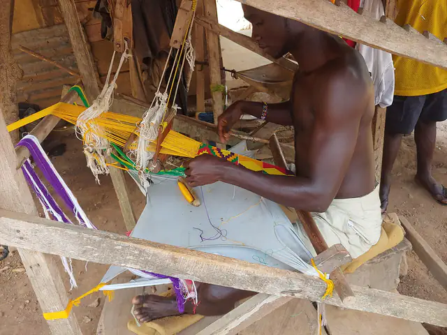 A weaver working at a loom in Bonwire